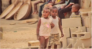 Deux jeunes enfants debout dans un environnement de construction, symbolisant l'innocence et la curiosité face au monde qui les entoure.